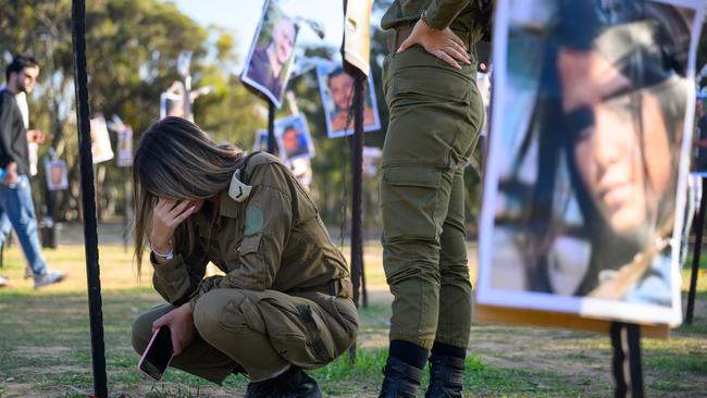 Soldiers react at a memorial display of photos of people killed during Hamas's attack on the Supernova festival at the site where the massacre took place.