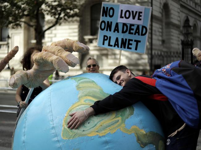 An Extinction Rebellion climate change protester hugs an inflatable planet Earth near Downing Street in London. Picture: Matt Dunham