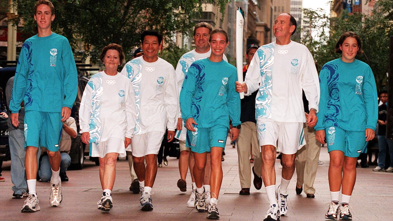 Former Olympian Herb Elliott holds the Olympic torch in Sydney as the escort uniforms are showcased for the 2000 Games. Picture: Marc McCormack