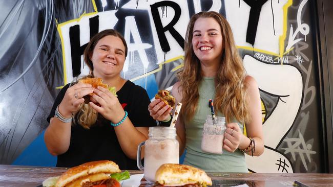 Sisters Sarah Paynter, 21, and Elizabeth Paynter, 15, enjoy a juicy burger and a milkshake together while holidaying in Cairns. Picture: Brendan Radke