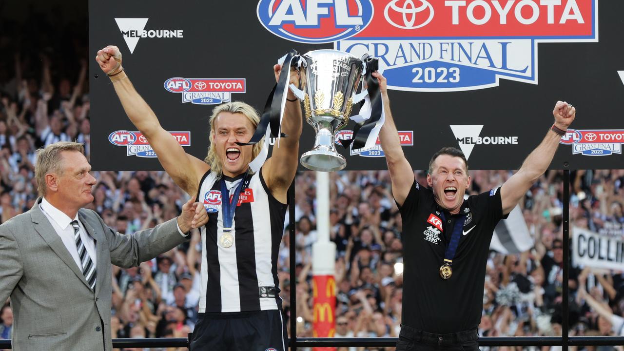 Collingwood’s Darcy Moore and Craig McRae hold aloft the premiership cup. Picture: Lachie Millard