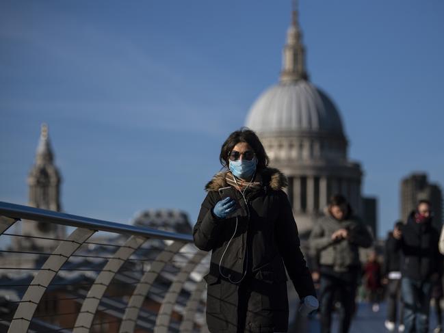 A woman crosses the millennium bridge in front of St Pauls Cathedral in London. Picture: Getty Images