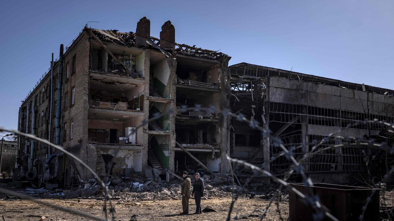 People stand beside damaged buildings at the Vizar company military-industrial complex in the town of Vyshneve, southwestern suburbs of Kyiv. Picture: FADEL SENNA / AFP