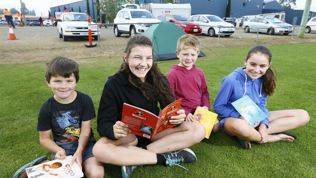 Adam Lockwood, left, Jaymee Lockwood, Lochlan Barry, Leah Lockwood, all of Geeveston, reading donated books outside the evacuation centre. Picture: MATT THOMPSON