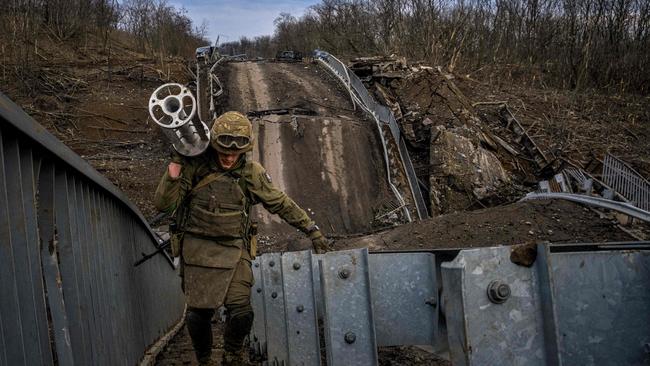 A Ukraine soldier carries an empty cluster cartridge of a Uragan missile while walking on a destroyed bridge near the city of Bakhmut. Picture: AFP.