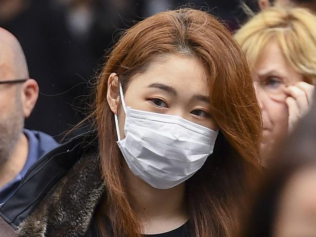 A woman wearing a face mask crosses the street in Melbourne on March 5, 2020. - Over 50 people have been confirmed to have the COVID-19 coronavirus in Australia so far with the latest cases including an eight-month-old baby in Adelaide. (Photo by William WEST / AFP)