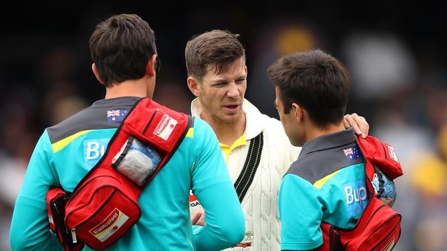 Tim Paine receives medical attention on his injured finger.
