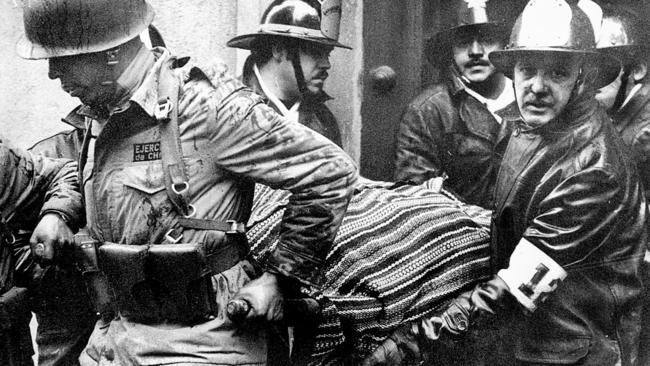 Soldiers and firefighters carry the body of Chilean president Salvador Allende, wrapped in a Bolivian poncho, out the destroyed presidential palace of La Moneda after the 1973 coup.