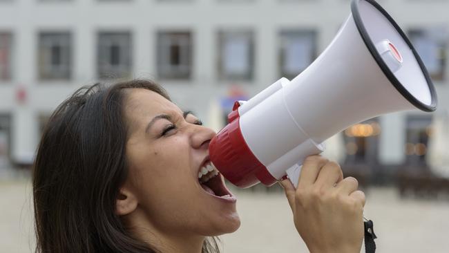 Woman yelling into a bullhorn on an urban street voicing her displaeasure during a protest or demonstration, close up side view of her face. Picture: iStock to go with question: Should I include my involvement with political and activist groups on my resume?