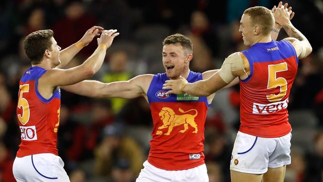 Pearce Hanley celebrates a goal with Dayne Zorko and Mitch Robinson.