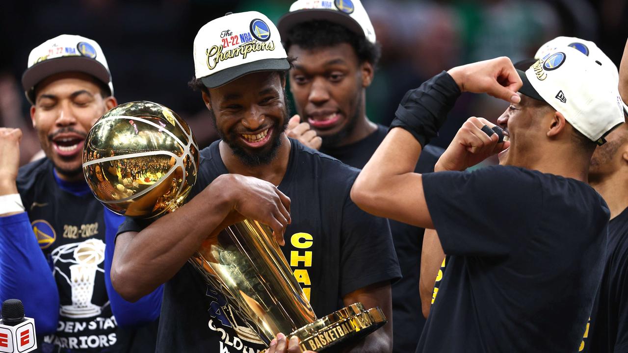 Andrew Wiggins and Jordan Poole celebrate with the Larry O'Brien Championship Trophy. Elsa/Getty Images/AFP