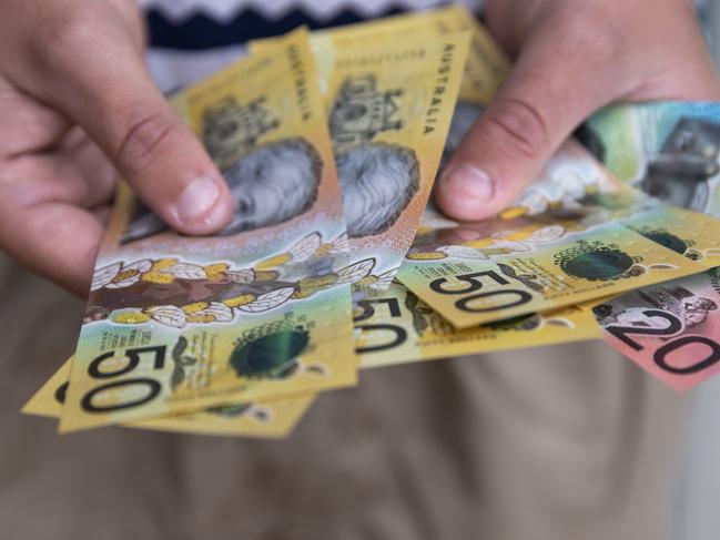 Male person holding some Australian currency. This visual concept evokes ideas around saving money, paying for expenses and investments.