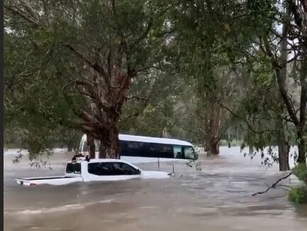 A mini bus is swept away and a ute is underwater at the Big 4 Caravan Park at Helensvale. Source: RNR Wanderers