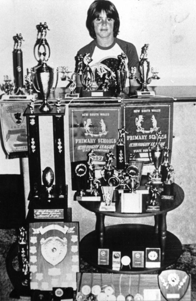 Fittler as proud schoolboy standing in front of numerous trophies won.