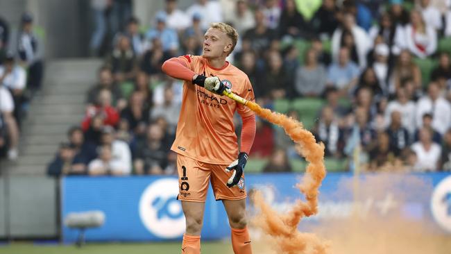 Melbourne City’s Tom Glover picks up a flare to remove it from the pitch. Picture: Darrian Traynor