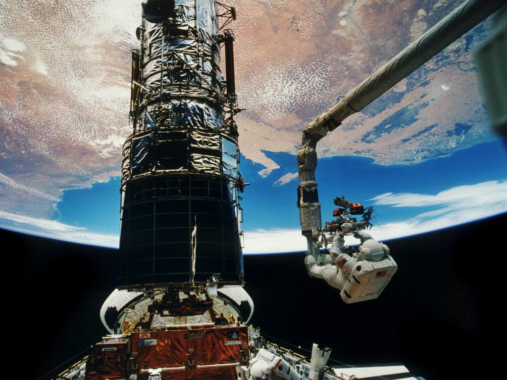 With South Australia’s St Vincents Gulf and Kangaroo Island as a backdrop, astronaut Story Musgrove is elevated to top of the Hubble Space Telescope on one of the several maintenance missions which have kept the groundbreaking satellite working. The telescope orbits 559km above the Earth.