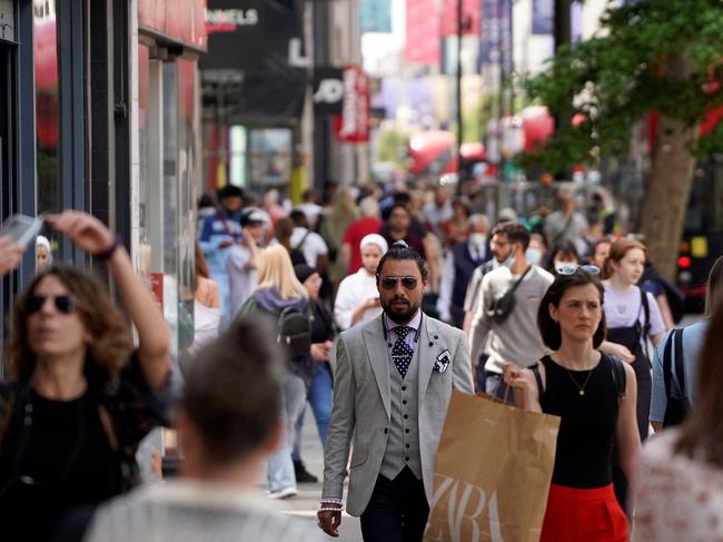 Pedestrians, some wearing face coverings due to Covid-19, walk past shops on Oxford Street in central London on June 7, 2021. - The Delta variant of the coronavirus, first discovered in India, is estimated to be 40 percent more transmissible than the Alpha variant that caused the last wave of infections in the UK, Britain's health minister said Sunday. (Photo by Niklas HALLE'N / AFP)