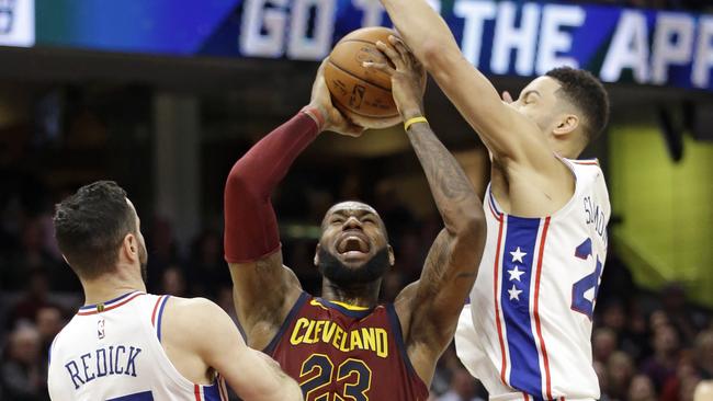 LeBron James shoots between Philadelphia 76ers' JJ Redick, left and Ben Simmons. (AP Photo/Tony Dejak)