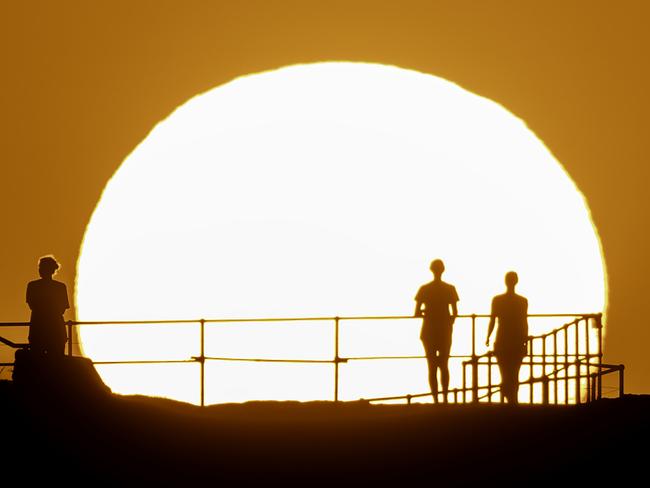 SYDNEY, AUSTRALIA - NOVEMBER 27: People watch as the sun rises over Ben Buckler Point in Bondi on November 27, 2024 in Sydney, Australia. Australians are at risk of enduring rolling blackouts this week, amid a heatwave sweeping through NSW and unexpected coal outages across the state. A severe heatwave warning has been issued by the Bureau of Meteorology for parts of eastern NSW over the next few days Ã¢â¬â with the mercury tipped to soar into the high 30s in some regions. Some areas reached a maximum temperature of 37C on Monday, with Richmond and Perth in Sydney's west also clocking in at 35C. (Photo by Brook Mitchell/Getty Images)