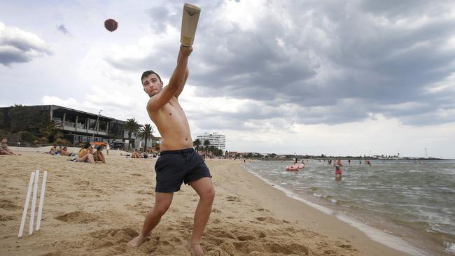 Claudio Sikora plays cricket with clouds closing in on St Kilda Beach. Picture: David Caird