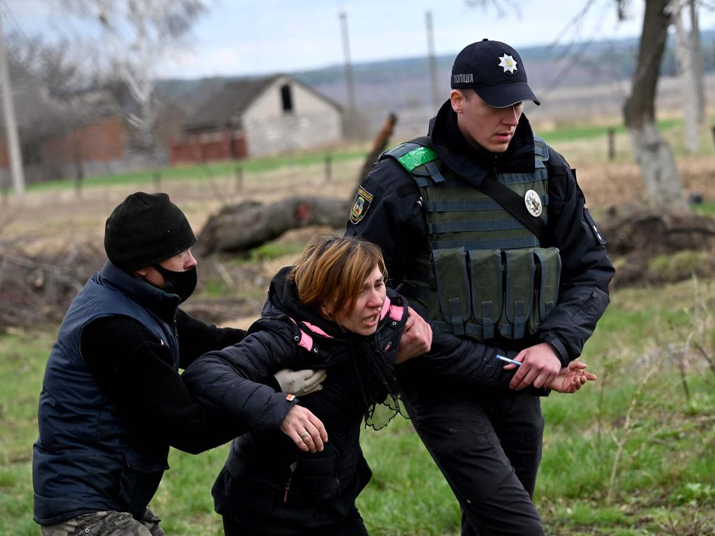 A police officer and another man help the woman. Picture: Sergei Supinsky /AFP