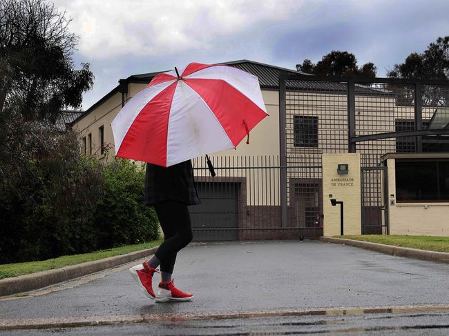 A man with an umbrella walking in the rain, as storm clouds gather over the French Embassy in Canberra. Picture: NewsWire/Gary Ramage