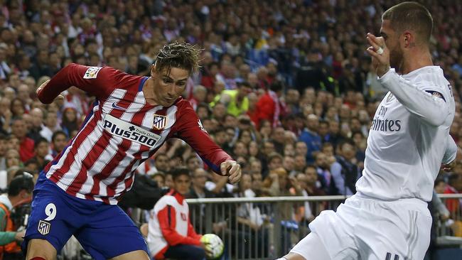 Atletico Madrid’s Fernando Torres is challenged by Real Madrid's Sergio Ramos.