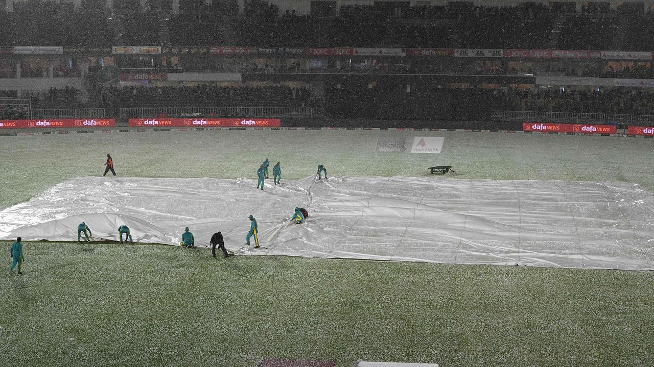 Ground staff cover the pitch after a hailstorm shower stopped the game. Photo by Aamir QURESHI / AFP