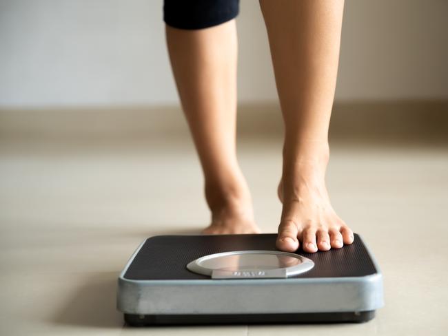 Female leg stepping on weigh scales. Healthy lifestyle, food and sport concept.