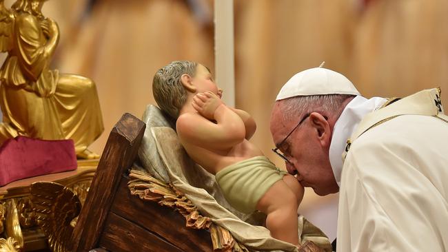 Pope Francis kisses a figurine of baby Jesus during Christmas Eve mass at St Peter's basilica in the Vatican City. Picture: Vincenzo Pinto