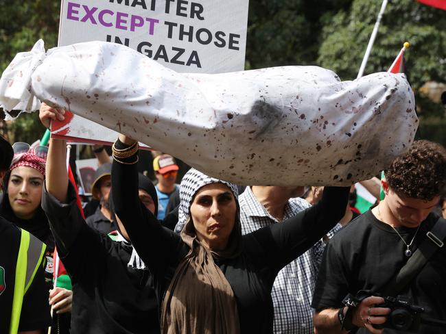 A woman hold up a mock body of a child wrapped in cloth. Picture: David Swift