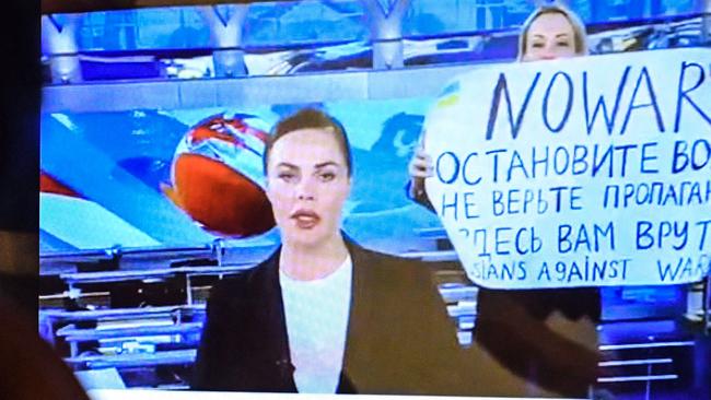 A dissenting Russian Channel One employee enters the on-air TV studio during Russia's most-watched evening news broadcast with anchor Yekaterina Andreyeva.