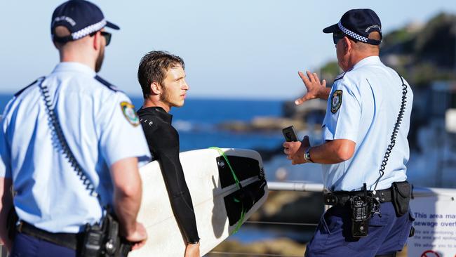 Police speak to a surfer at Bondi Beach yesterday. Picture: Gaye Gerard