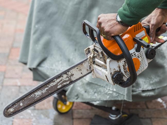 An artist with a chainsaw getting ready to carve something out of a block of ice.