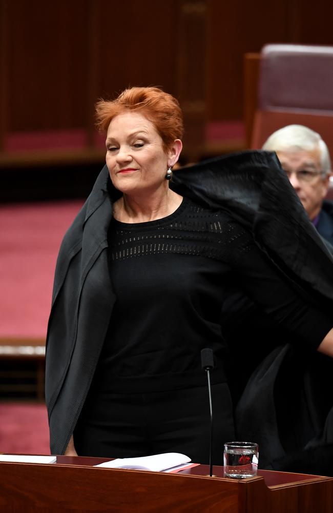 Senator Hanson reveals her face as she takes off a burqa during Question Time. Picture: AAP