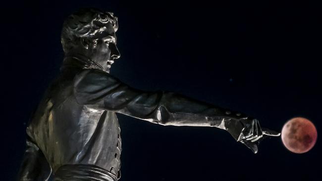 Blood Moon last night in Adelaide , with the Colonel Light Statue . Picture : Steven Genesin