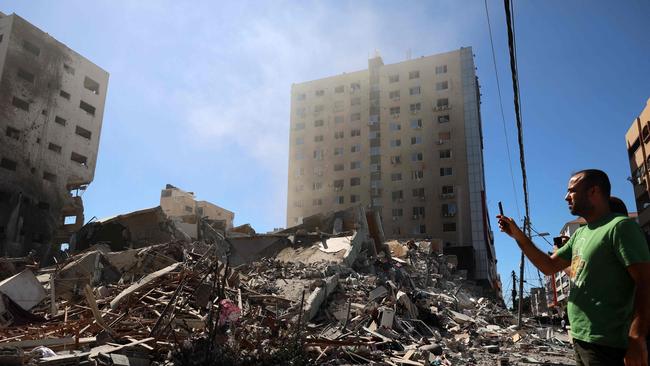 A Palestinian man takes a photograph with his mobile phone of a building hit and destroyed during an Israeli Air strike in Gaza City, on May 15. Picture: AFP