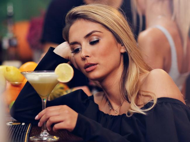 Picture showing young woman sitting alone in bar with a coctail