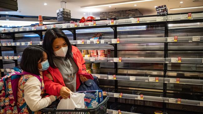 Customers wear face masks as they walk past empty shelves in a grocery store in Hong Kong, China. (Photo by Anthony Kwan/Getty Images)