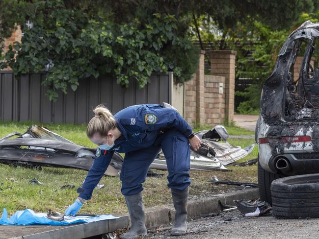 Forensics police officers examine the scene of a burnt out car which was used in the fatal shootings of two women in Sydney's southwest. Picture: NCA NewsWire / Monique Harmer