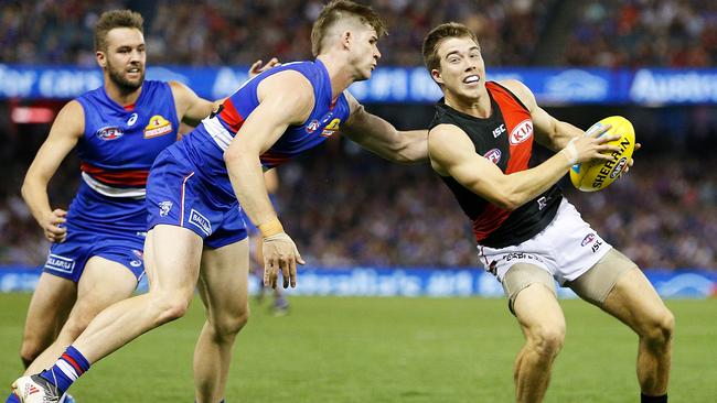 Billy Gowers of the Bulldogs tackles Zach Merrett of the Bombers.