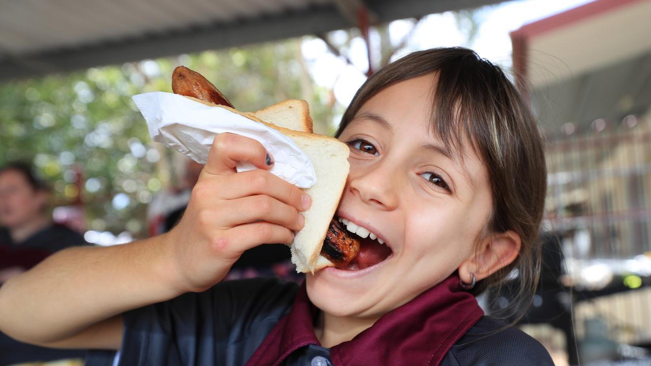 Maisie Taylor, 9, hooks into a sausage sanga at Lognholme State School. Picture: Scott Powick