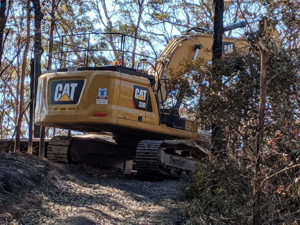 An excavator works to removed damaged trees. Picture: Luke Mortimer.