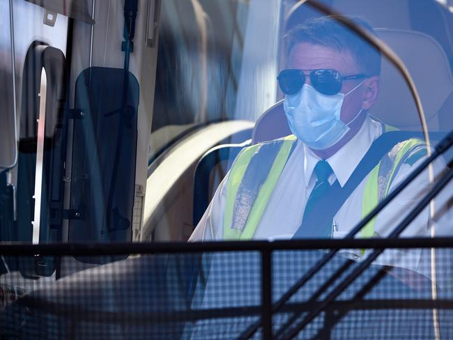A charter bus driving wearing a mask is seen waiting to take Australian residents returning from India to begin their 14-day imposed quarantine, after arriving at Sydney International Airport in Sydney, Friday, May 8, 2020. (AAP Image/Bianca De Marchi) NO ARCHIVING