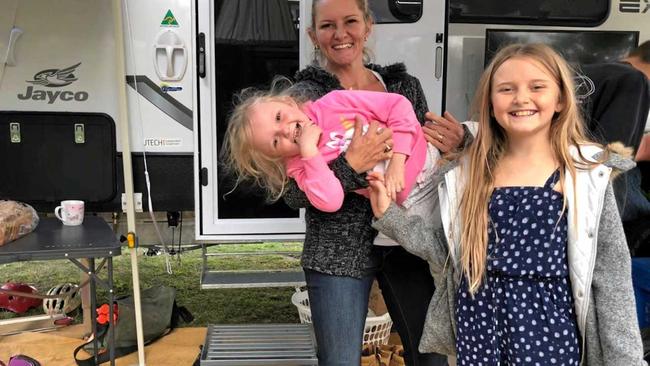 Harper Loadsman, who was the beneficiary of life-saving blood donations, in the arms of her mother Jana with sister Mia while camping in Ballina.