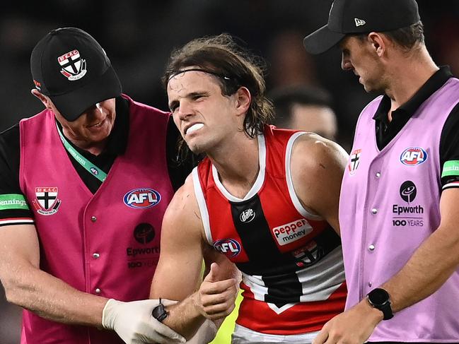 MELBOURNE, AUSTRALIA - MARCH 05: Hunter Clark of the Saints is helped from the ground by trainers during the AFL AAMI Community Series match between the Essendon Bombers and the St Kilda Saints at Marvel Stadium on March 05, 2022 in Melbourne, Australia. (Photo by Quinn Rooney/Getty Images)