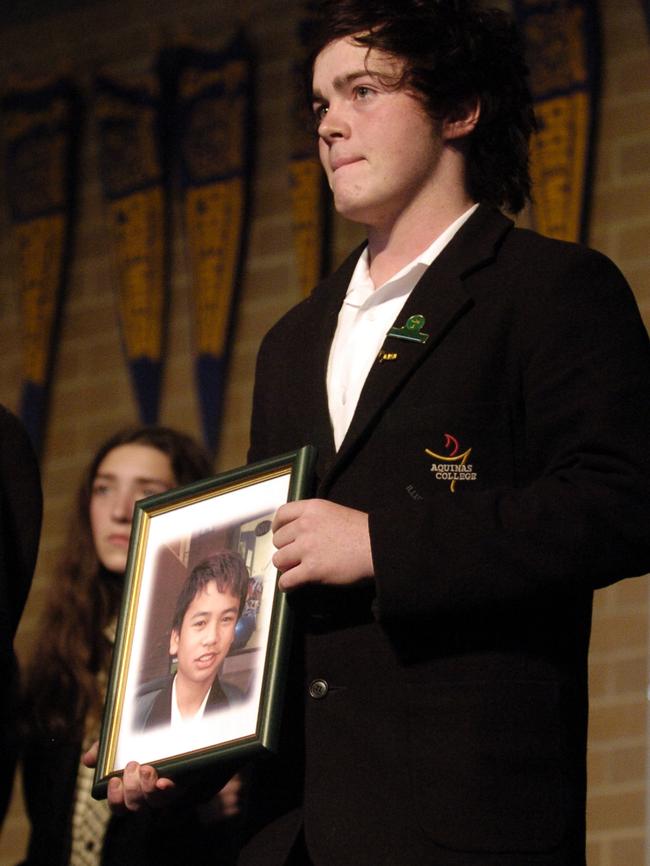 Aquinas College school captain Ash Woodward holds a photo of Kyle Vassil at his memorial.
