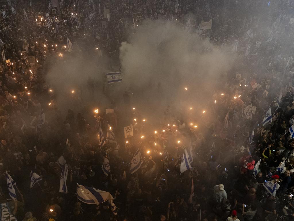 Protesters hold flame torches and set a fire as they are taking part in a demonstration calling for the release of hostages held in the Gaza Strip.