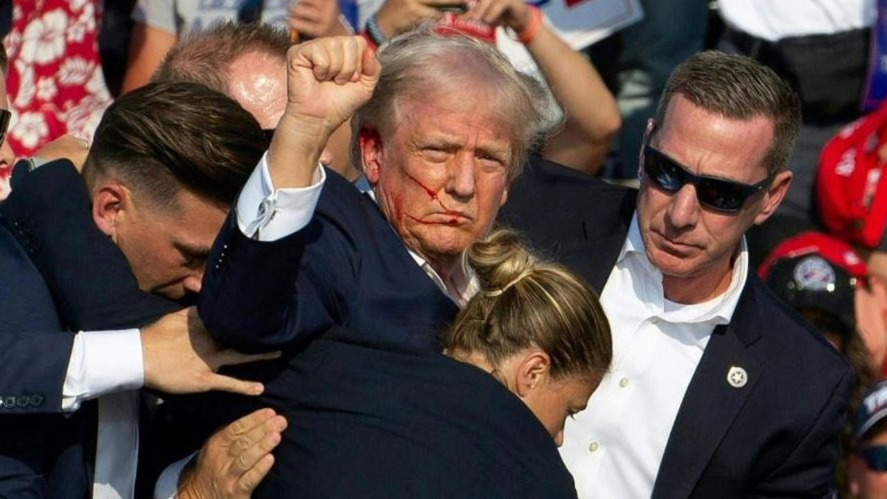 Donald Trump ducked down as Secret Service agents flooded the stage during an assassination attempt in July. Picture: Getty