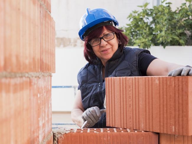 mature woman bricklayer lays bricks in the construction and remodeling of the terrace room of a house. Picture: iStock